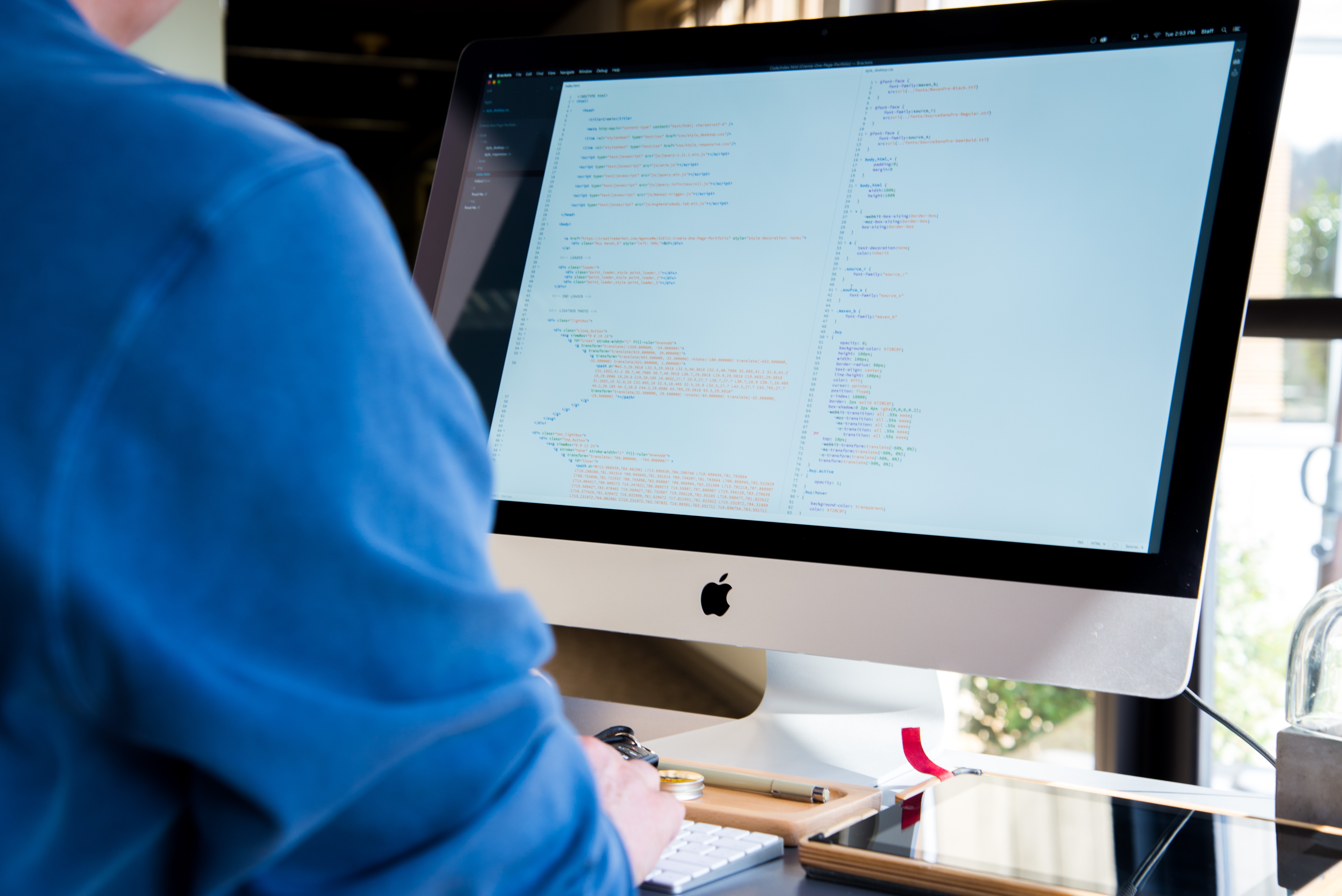 Over the shoulder shot of Mac computer with code on screen.